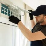 Signs AC Overworking Houston: HVAC technician inspecting an indoor air conditioning unit