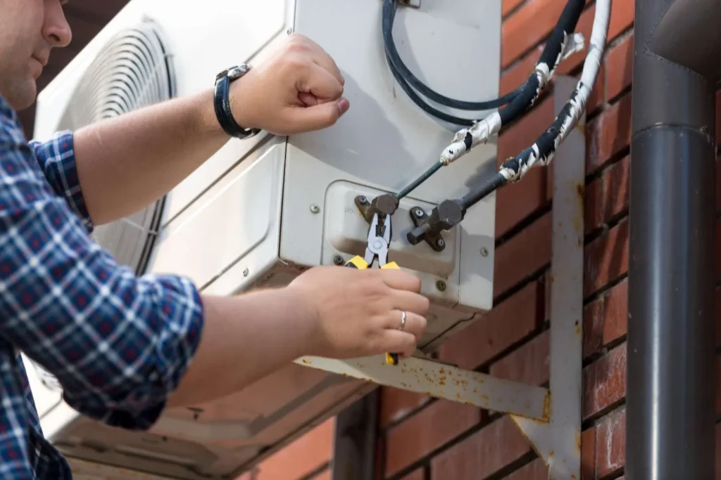 How to fix heating and air conditioning system with a technician repairing an outdoor AC condenser unit