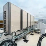 HVAC system components including rooftop commercial condensing units, refrigerant lines, electrical connections, and support framework installation