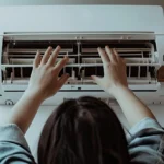 Why is my AC not blowing cold air? Homeowner inspecting and cleaning an indoor air conditioner unit