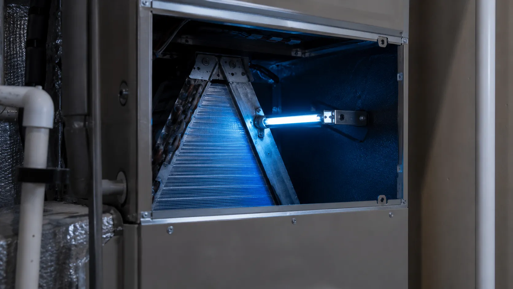 Installed HVAC ultraviolet lamp glowing blue near evaporator coils to evaluate are UV lights necessary for AC units in preventing mold and bacteria growth.
