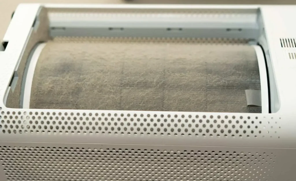 A close-up of a heavily clogged, dusty air purifier barrel showing how does a HEPA filter work by trapping airborne particles.
