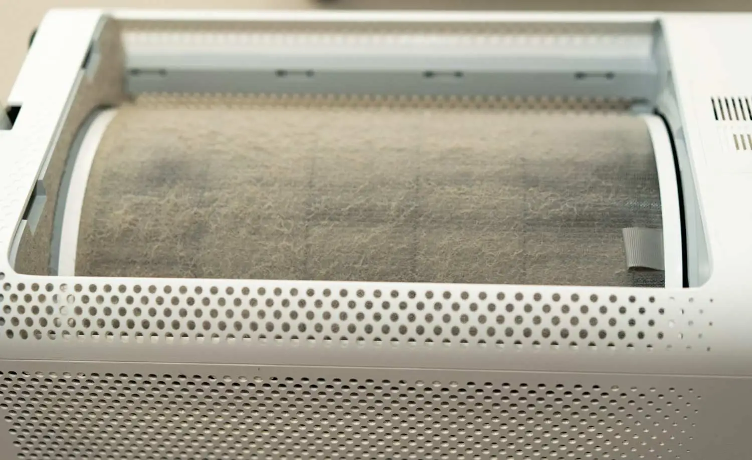 A close-up of a heavily clogged, dusty air purifier barrel showing how does a HEPA filter work by trapping airborne particles.