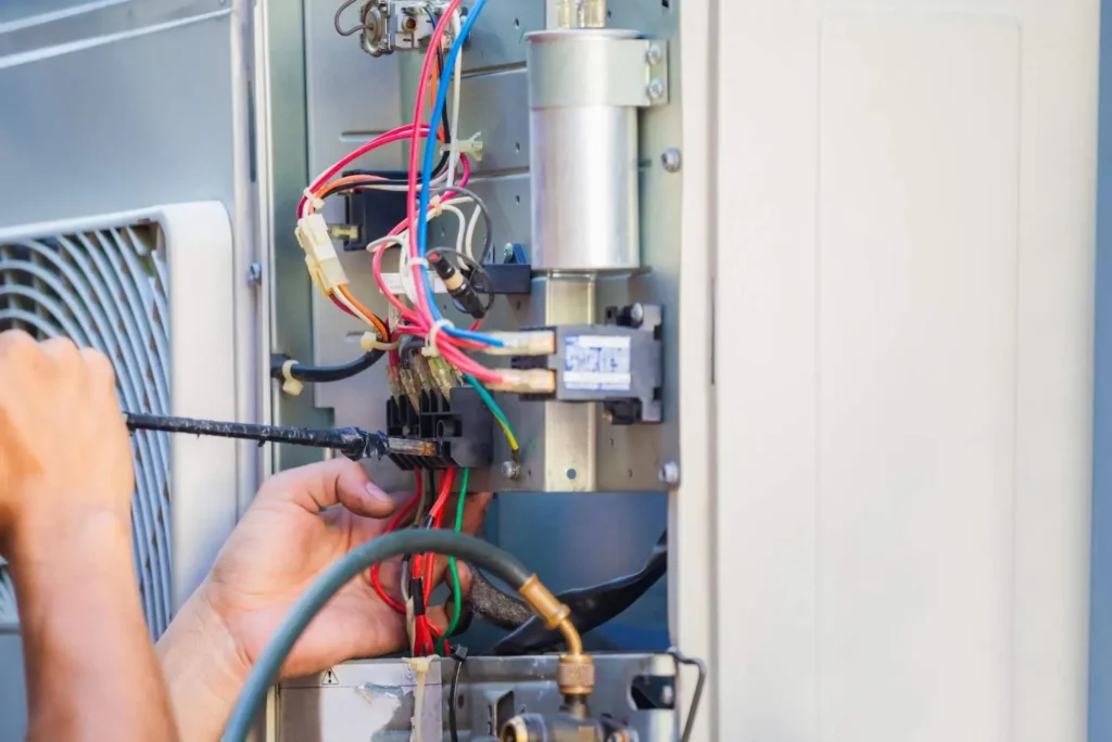A technician carefully wiring complex electrical components and terminal blocks, demonstrating an important step in how to install electric furnace systems safely.