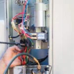 A technician carefully wiring complex electrical components and terminal blocks, demonstrating an important step in how to install electric furnace systems safely.