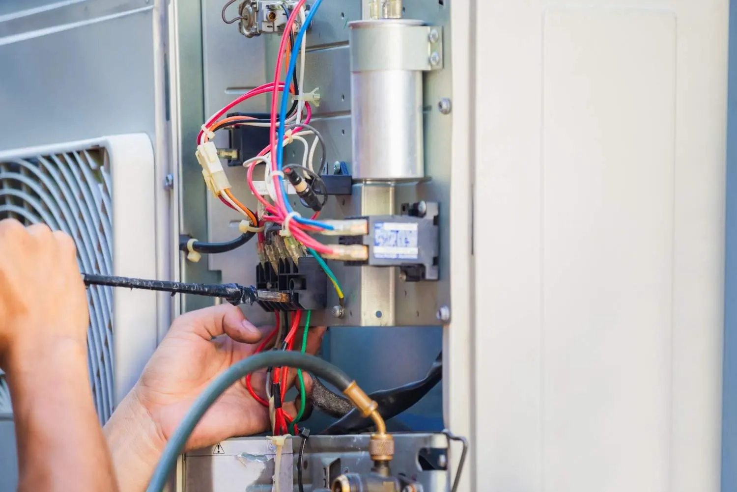 A technician carefully wiring complex electrical components and terminal blocks, demonstrating an important step in how to install electric furnace systems safely.