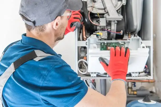 HVAC technician performing maintenance to demonstrate how to reset furnace safely