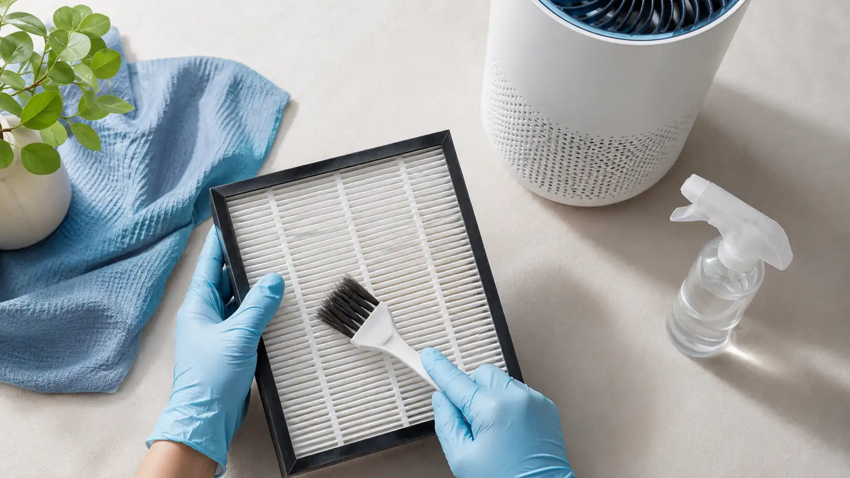 Person wearing blue gloves using a small brush to show how to clean a hepa filter.