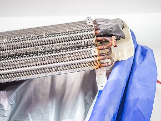 Professional cleaning AC evaporator coils during maintenance service