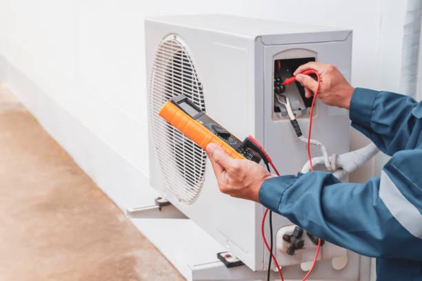 Professional HVAC technician diagnosing AC problem with diagnostic equipment at night