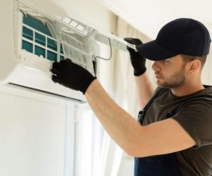 Signs AC Overworking Houston: HVAC technician inspecting an indoor air conditioning unit