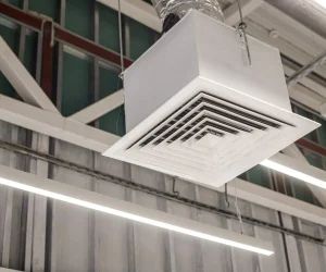 A close-up of a square grid supply ventilation duct in a commercial ceiling, illustrating the