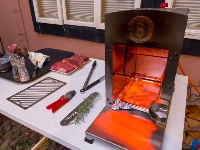 A high-heat tabletop infrared broiler glowing bright orange, used to demonstrate what is a furnace style cooking appliance for searing steaks.